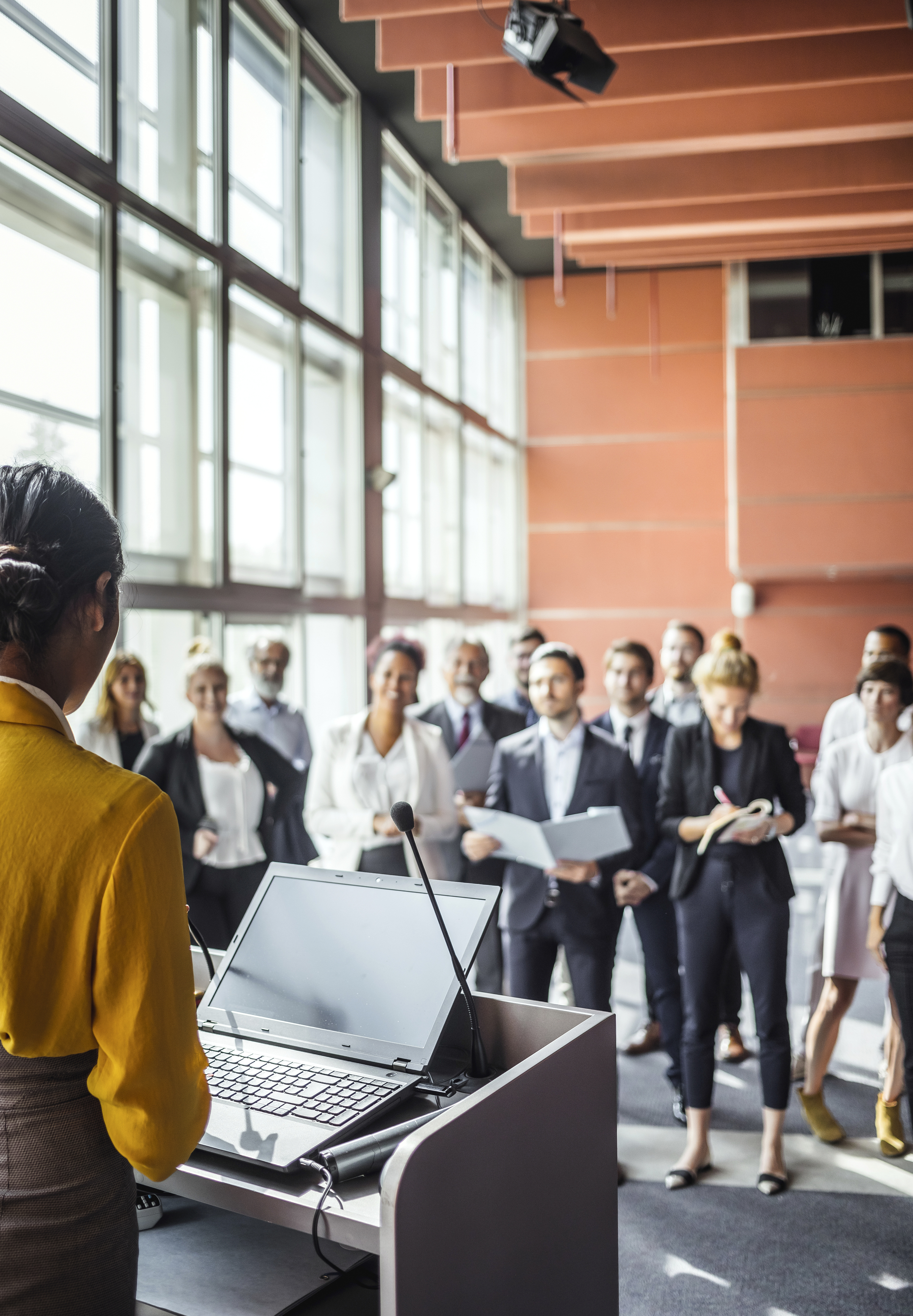 Woman leaders peaking at podium in front of staff